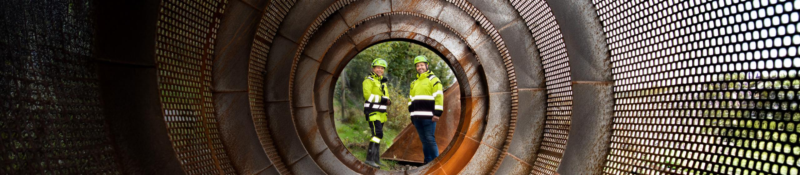 Two people standing at the end of a circled tunnel