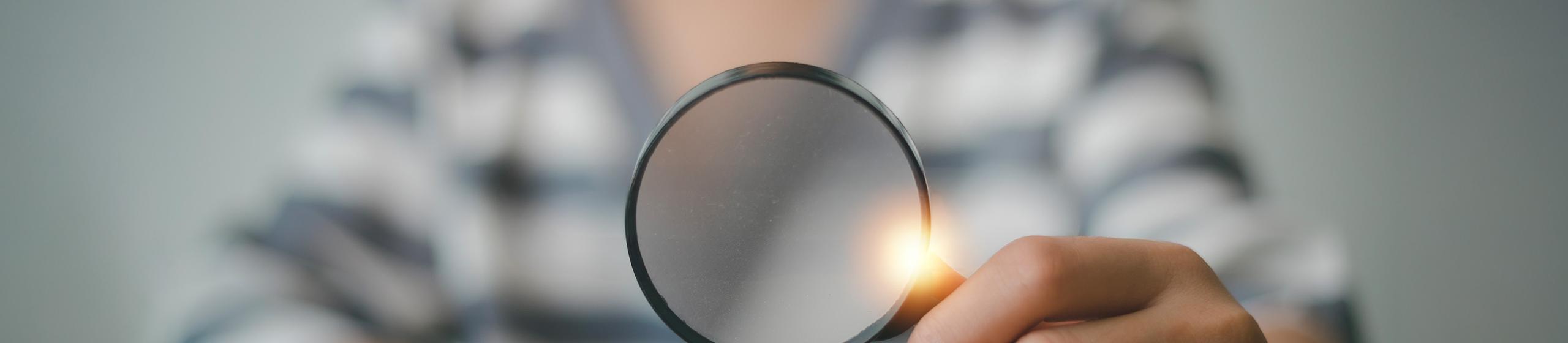 Hand holding a magnifying glass